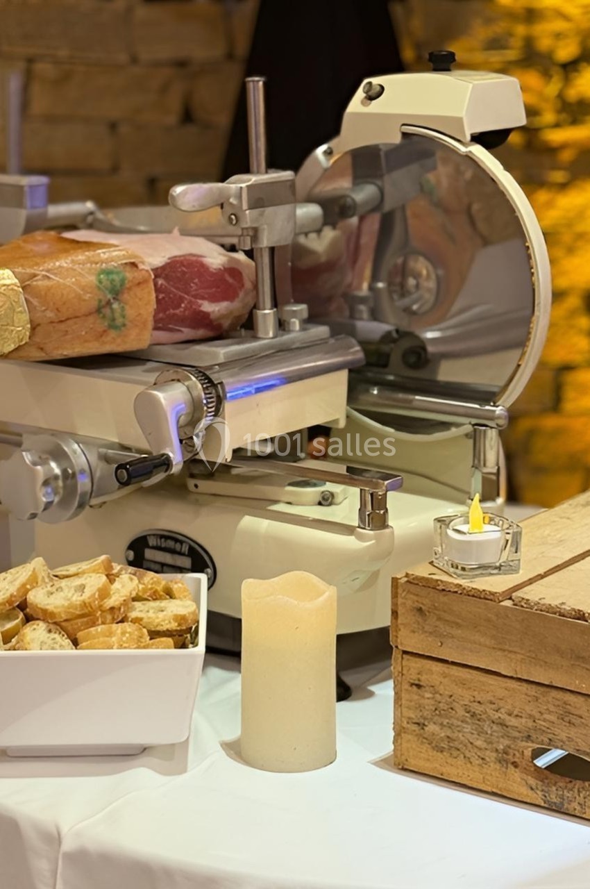 Trancheuse à jambon en action avec une bougie, des morceaux de pain et une caisse en bois sur une table.