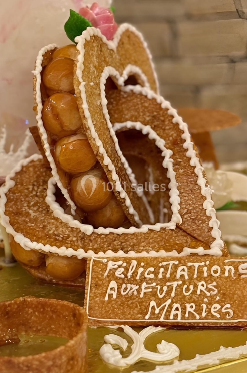 Pièce montée en forme de cœur avec des choux et du caramel, décorée d’un message ’Félicitations aux futurs mariés’.
