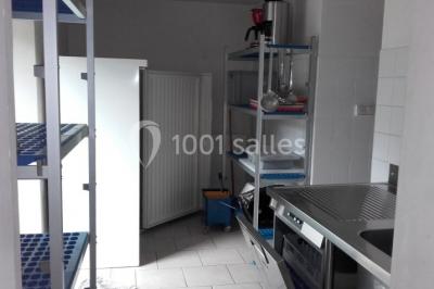 Bouteilles de jus de pomme, pot de confiture et noix disposés sur une nappe rouge à pois, avec un plat vert en arrière-plan.