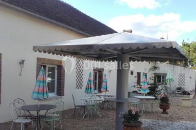 Bouteilles de jus de pomme, pot de confiture et noix disposés sur une nappe rouge à pois, avec un plat vert en arrière-plan.