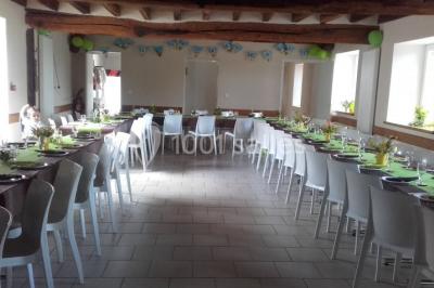 Bouteilles de jus de pomme, pot de confiture et noix disposés sur une nappe rouge à pois, avec un plat vert en arrière-plan.