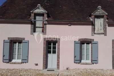 Bouteilles de jus de pomme, pot de confiture et noix disposés sur une nappe rouge à pois, avec un plat vert en arrière-plan.