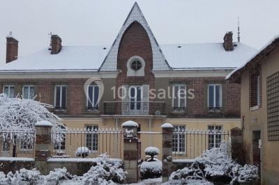 Bouteilles de jus de pomme, pot de confiture et noix disposés sur une nappe rouge à pois, avec un plat vert en arrière-plan.