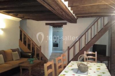 Bouteilles de jus de pomme, pot de confiture et noix disposés sur une nappe rouge à pois, avec un plat vert en arrière-plan.