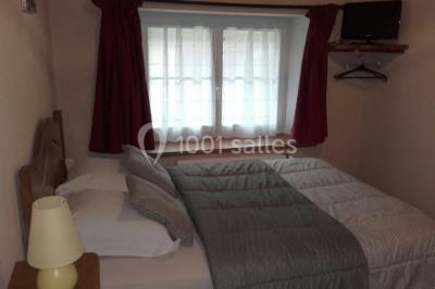 Bouteilles de jus de pomme, pot de confiture et noix disposés sur une nappe rouge à pois, avec un plat vert en arrière-plan.