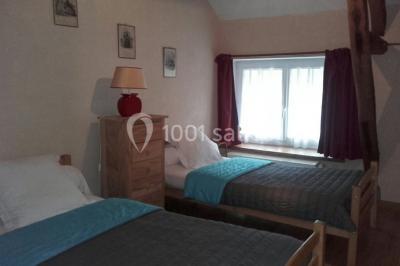 Bouteilles de jus de pomme, pot de confiture et noix disposés sur une nappe rouge à pois, avec un plat vert en arrière-plan.