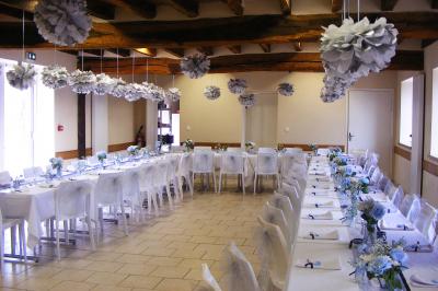 Bouteilles de jus de pomme, pot de confiture et noix disposés sur une nappe rouge à pois, avec un plat vert en arrière-plan.