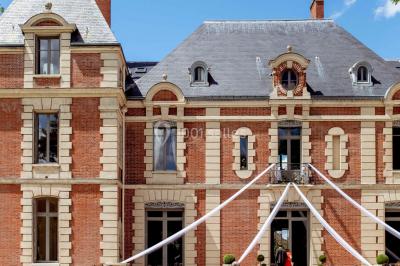 Façade d'un château éclairé au crépuscule, vue depuis un parterre de fleurs au premier plan.