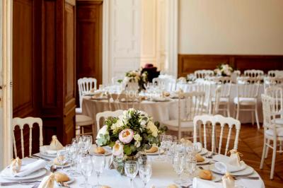 Façade d'un château éclairé au crépuscule, vue depuis un parterre de fleurs au premier plan.