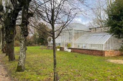 Façade d'un château éclairé au crépuscule, vue depuis un parterre de fleurs au premier plan.
