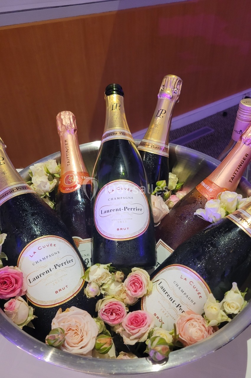 Bouteilles de champagne Laurent-Perrier disposées dans un seau en métal avec des roses décoratives.