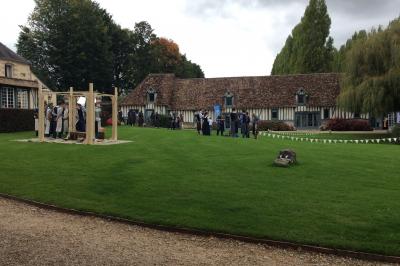 Platines vinyles et disques exposés sur une table en extérieur, avec un jardin verdoyant et un pigeonnier à colombages en…