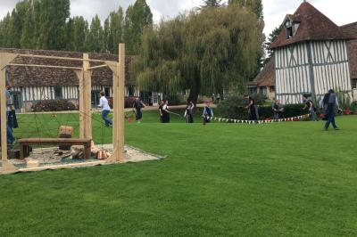 Platines vinyles et disques exposés sur une table en extérieur, avec un jardin verdoyant et un pigeonnier à colombages en…