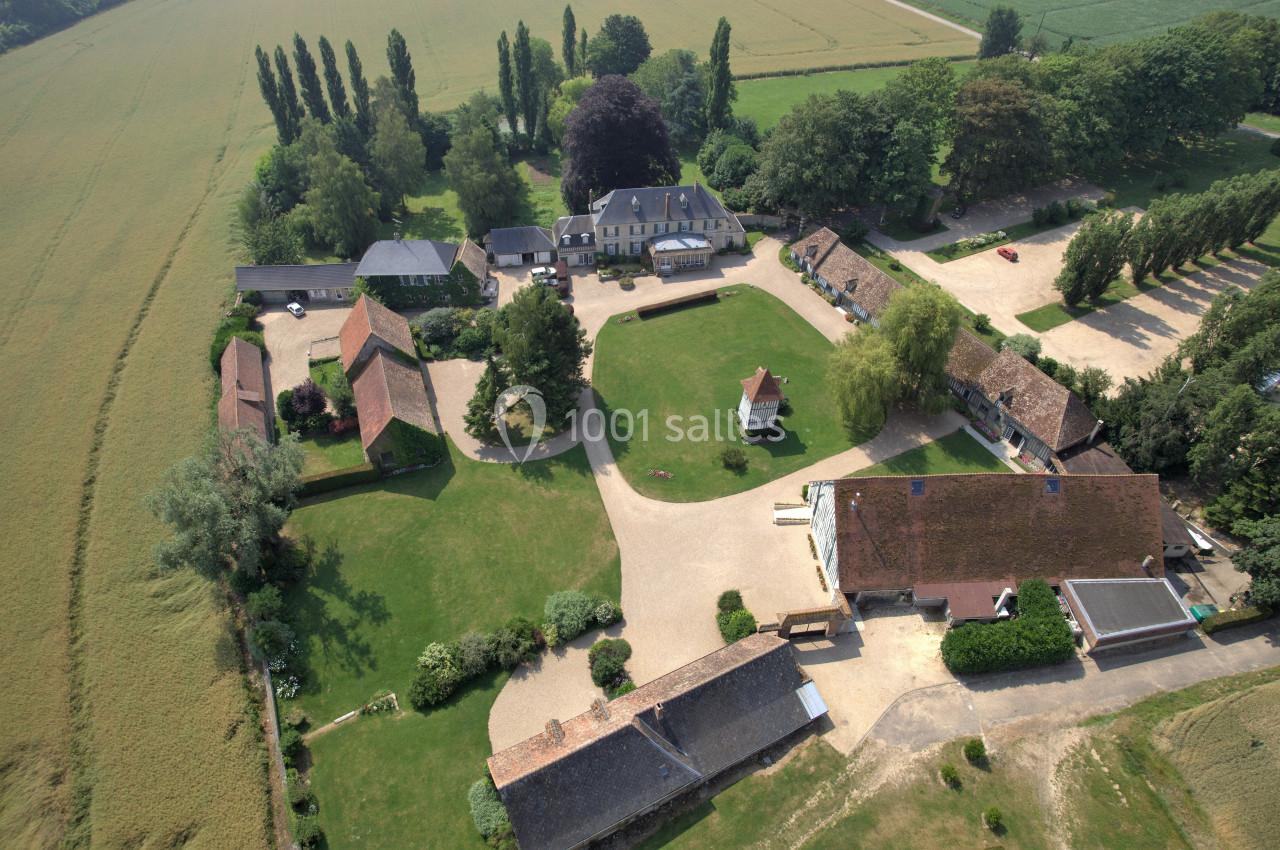 Vue aérienne d'un domaine rural avec bâtiments en pierre, cours, pelouses et champs environnants.