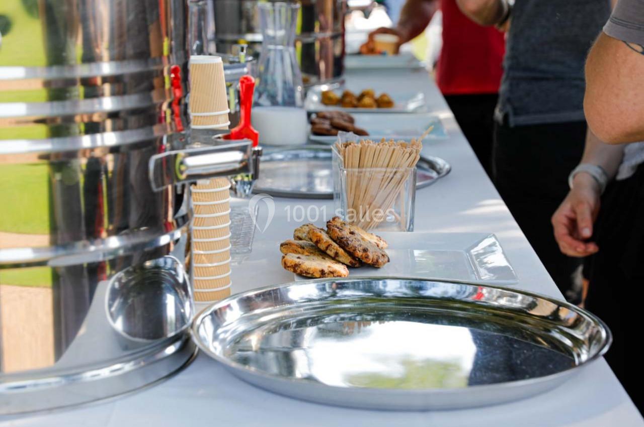 Plateau de biscuits et gobelets en carton sur une table de buffet avec distributeurs de boissons en arrière-plan.
