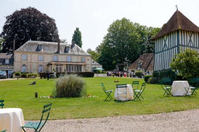 Platines vinyles et disques exposés sur une table en extérieur, avec un jardin verdoyant et un pigeonnier à colombages en…
