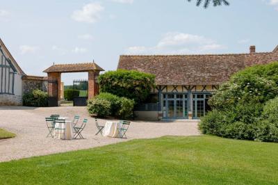 Platines vinyles et disques exposés sur une table en extérieur, avec un jardin verdoyant et un pigeonnier à colombages en…