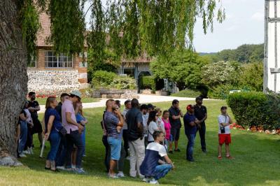 Platines vinyles et disques exposés sur une table en extérieur, avec un jardin verdoyant et un pigeonnier à colombages en…