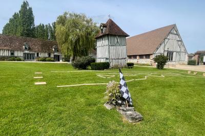Platines vinyles et disques exposés sur une table en extérieur, avec un jardin verdoyant et un pigeonnier à colombages en…