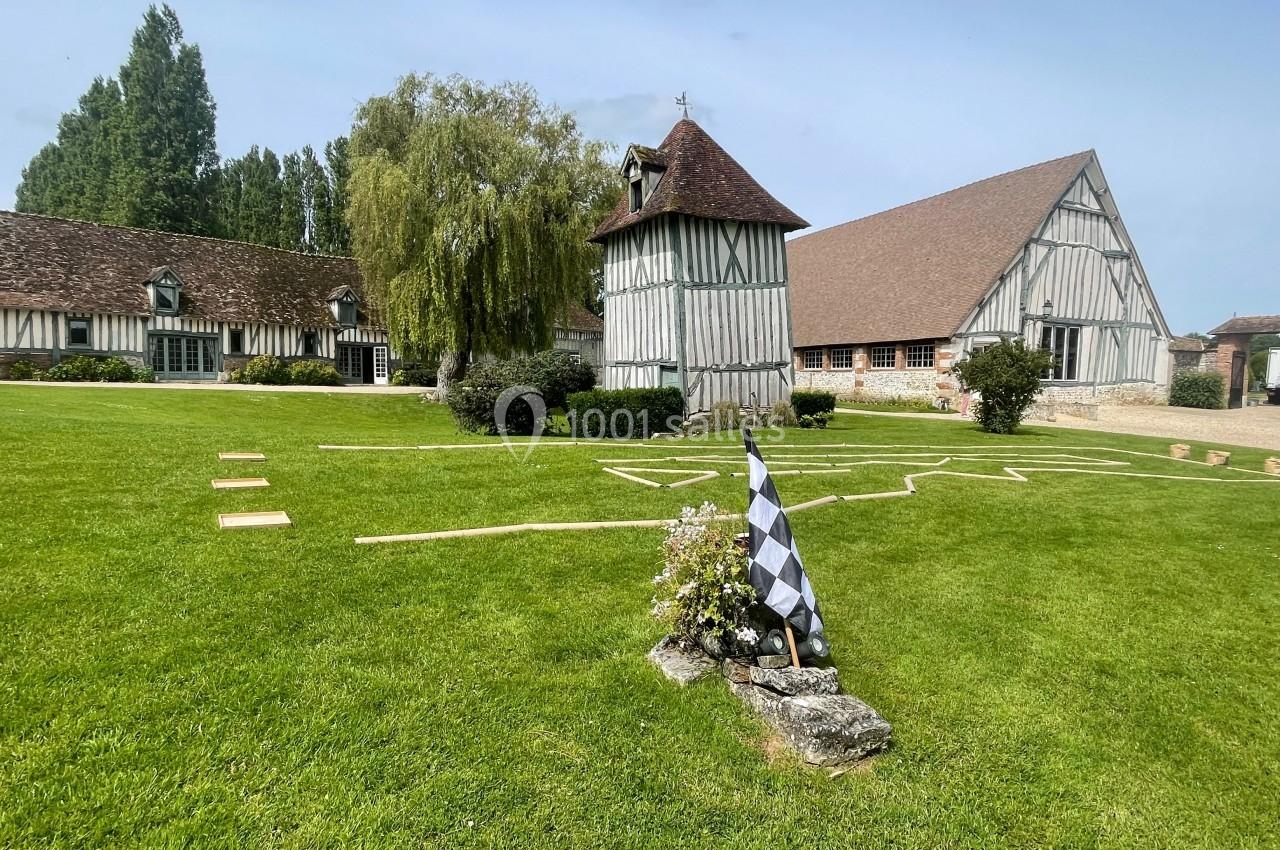 Bâtiments à colombages entourés de pelouses, avec un drapeau à damier et des chemins tracés au sol.