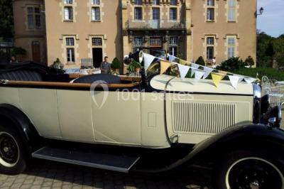 Des personnes en tenue traditionnelle dansent et célèbrent en extérieur, devant des bâtiments en pierre et végétation.