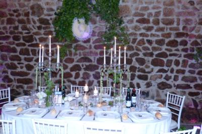 Des personnes en tenue traditionnelle dansent et célèbrent en extérieur, devant des bâtiments en pierre et végétation.