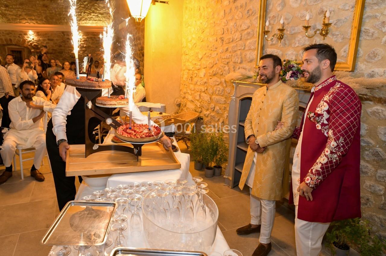 Un serveur présente des desserts décorés de feux d'artifice lors d'une célébration dans une salle en pierre.