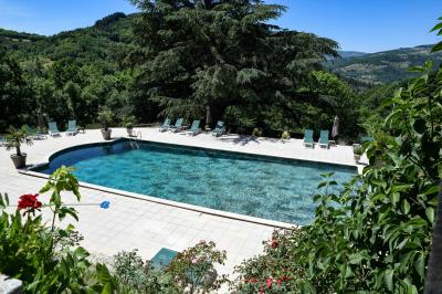 Des personnes en tenue traditionnelle dansent et célèbrent en extérieur, devant des bâtiments en pierre et végétation.