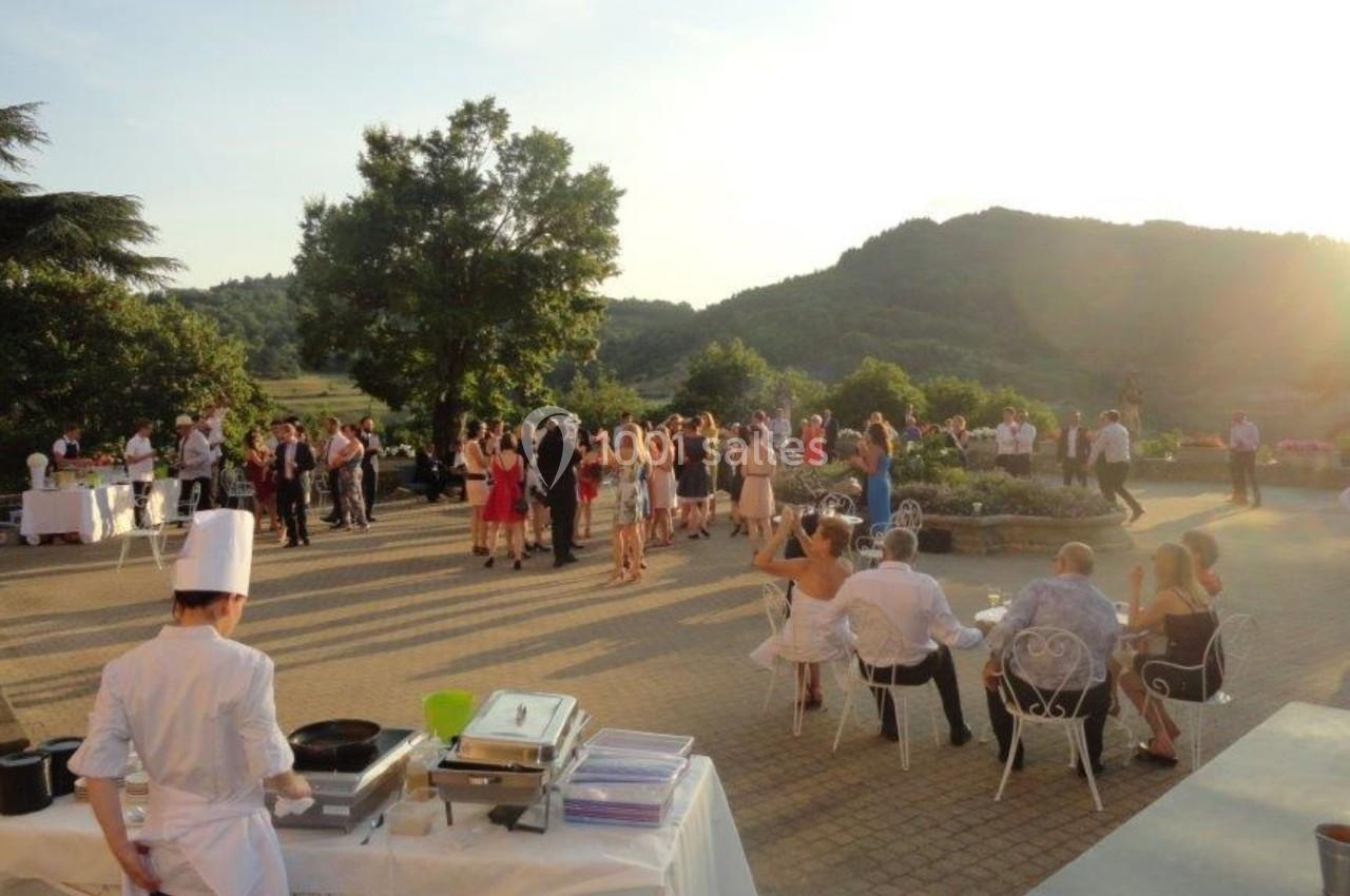 Groupe de personnes rassemblées en extérieur lors d'une réception au coucher du soleil, avec un chef cuisinant au premier…