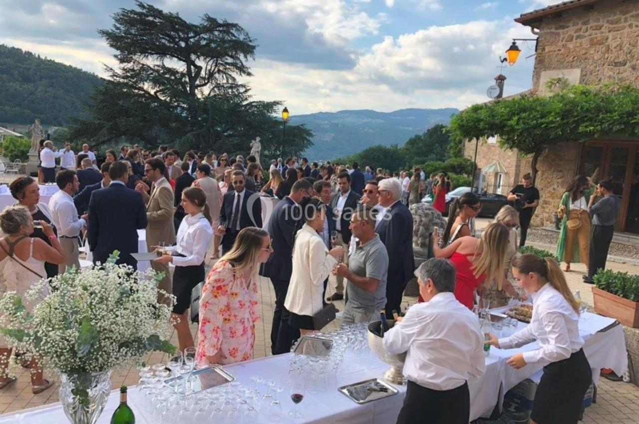 Groupe de personnes rassemblées en extérieur lors d'un événement, avec buffet et paysage vallonné en arrière-plan.