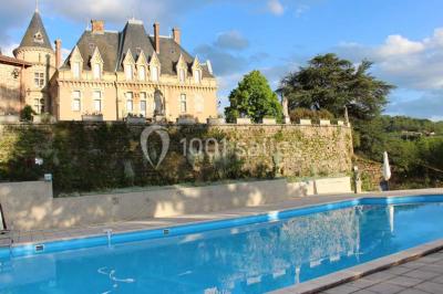 Façade d'un bâtiment ancien avec des arches vitrées, entouré de végétation et d'un escalier sur la gauche.