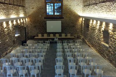 Façade d'un bâtiment ancien avec des arches vitrées, entouré de végétation et d'un escalier sur la gauche.