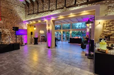 Façade d'un bâtiment ancien avec des arches vitrées, entouré de végétation et d'un escalier sur la gauche.