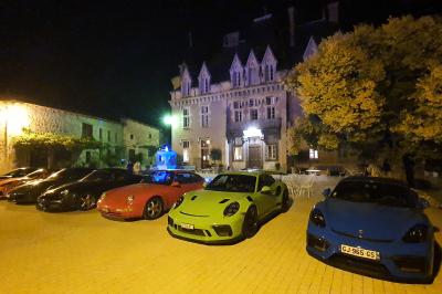 Façade d'un bâtiment ancien avec des arches vitrées, entouré de végétation et d'un escalier sur la gauche.
