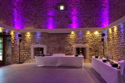 Façade d'un bâtiment ancien avec des arches vitrées, entouré de végétation et d'un escalier sur la gauche.