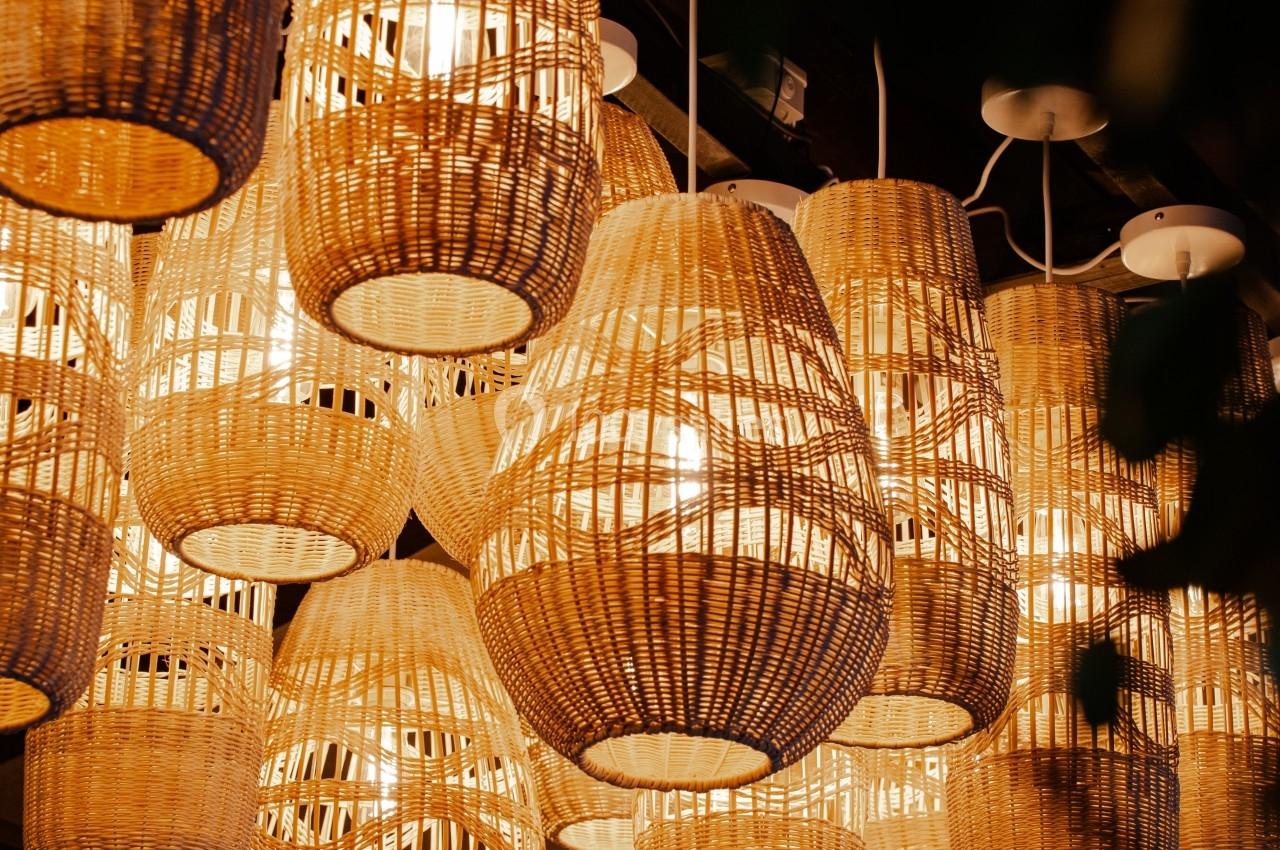 Suspensions en osier éclairées, accrochées au plafond dans une ambiance chaleureuse et tamisée.