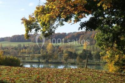 Paysage automnal avec un lac entouré de collines boisées et d'arbres aux feuilles colorées.