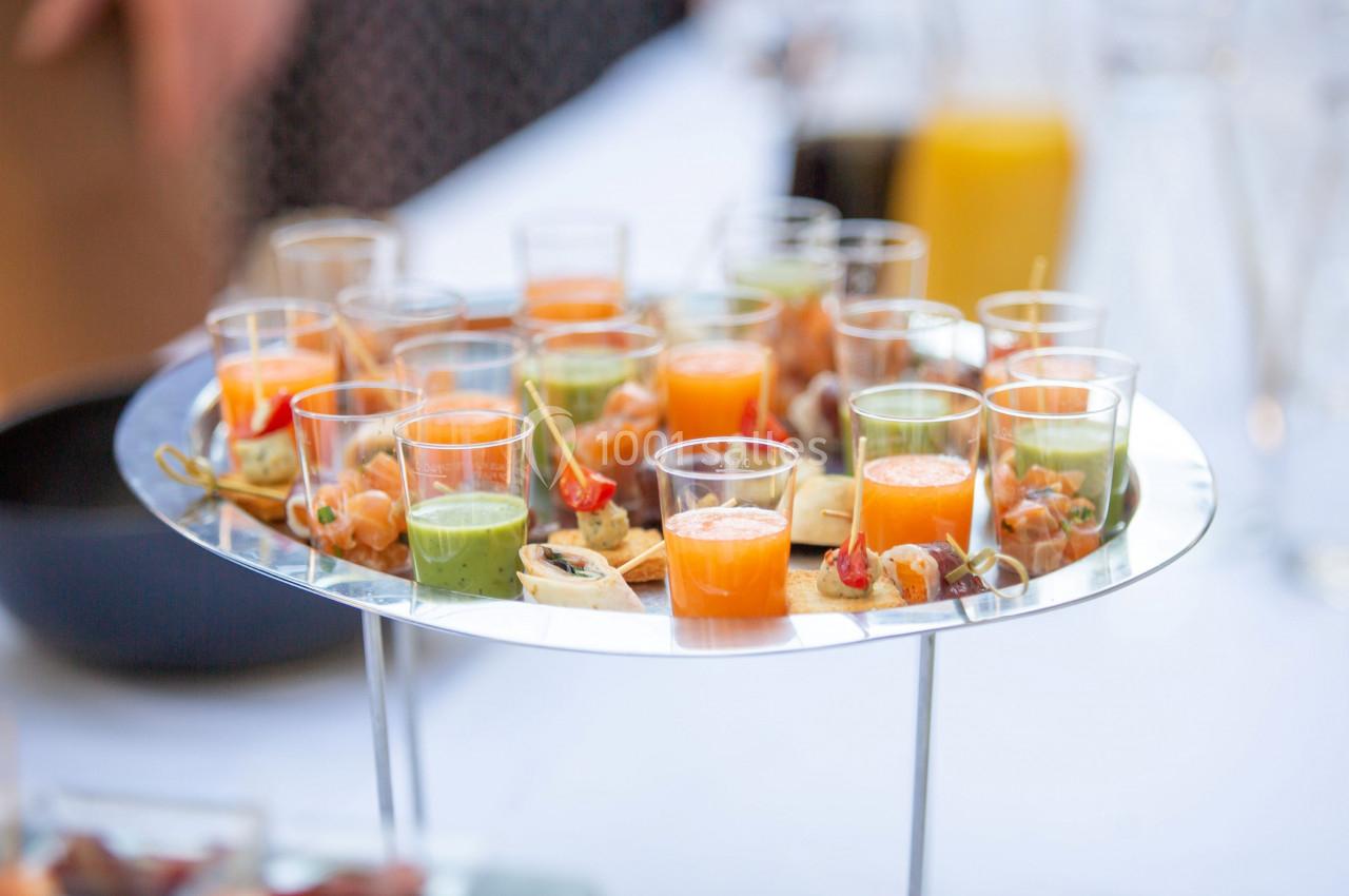 Plateau de verrines colorées contenant des soupes et des amuse-bouches, présenté sur une table lors d'un événement.
