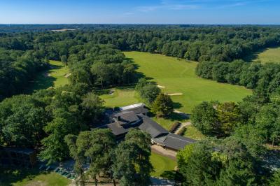 Salle de réception décorée pour un mariage, avec des tables rondes dressées, nappes blanches et arrangements floraux.