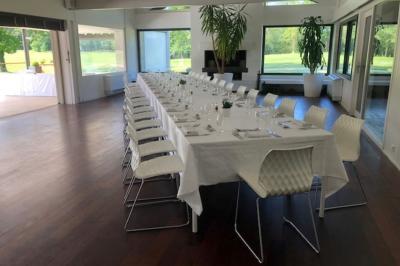 Salle de réception décorée pour un mariage, avec des tables rondes dressées, nappes blanches et arrangements floraux.