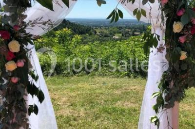 Salle en bois avec des bancs alignés sur un sol en gazon synthétique, décorée de fleurs suspendues.