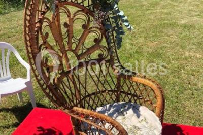 Salle en bois avec des bancs alignés sur un sol en gazon synthétique, décorée de fleurs suspendues.