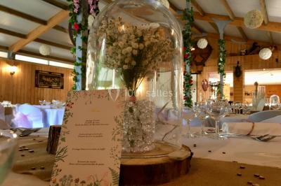 Salle en bois avec des bancs alignés sur un sol en gazon synthétique, décorée de fleurs suspendues.
