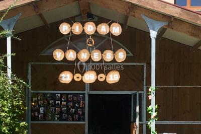 Salle en bois avec des bancs alignés sur un sol en gazon synthétique, décorée de fleurs suspendues.