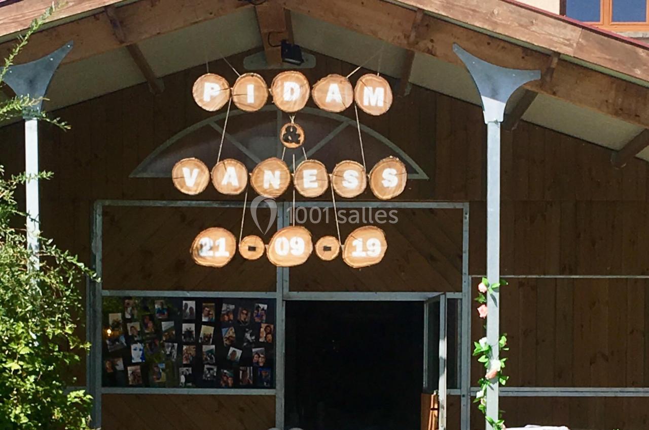 Entrée décorée d'une salle de réception avec des panneaux en bois affichant des prénoms et une date, ballons blancs en…