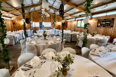Salle en bois avec des bancs alignés sur un sol en gazon synthétique, décorée de fleurs suspendues.