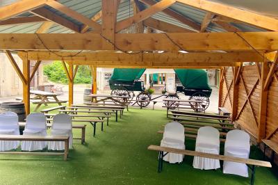 Salle en bois avec des bancs alignés sur un sol en gazon synthétique, décorée de fleurs suspendues.