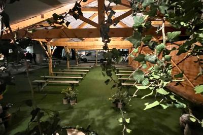 Salle en bois avec des bancs alignés sur un sol en gazon synthétique, décorée de fleurs suspendues.