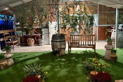 Salle en bois avec des bancs alignés sur un sol en gazon synthétique, décorée de fleurs suspendues.