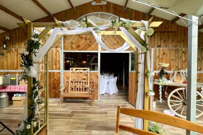 Salle en bois avec des bancs alignés sur un sol en gazon synthétique, décorée de fleurs suspendues.